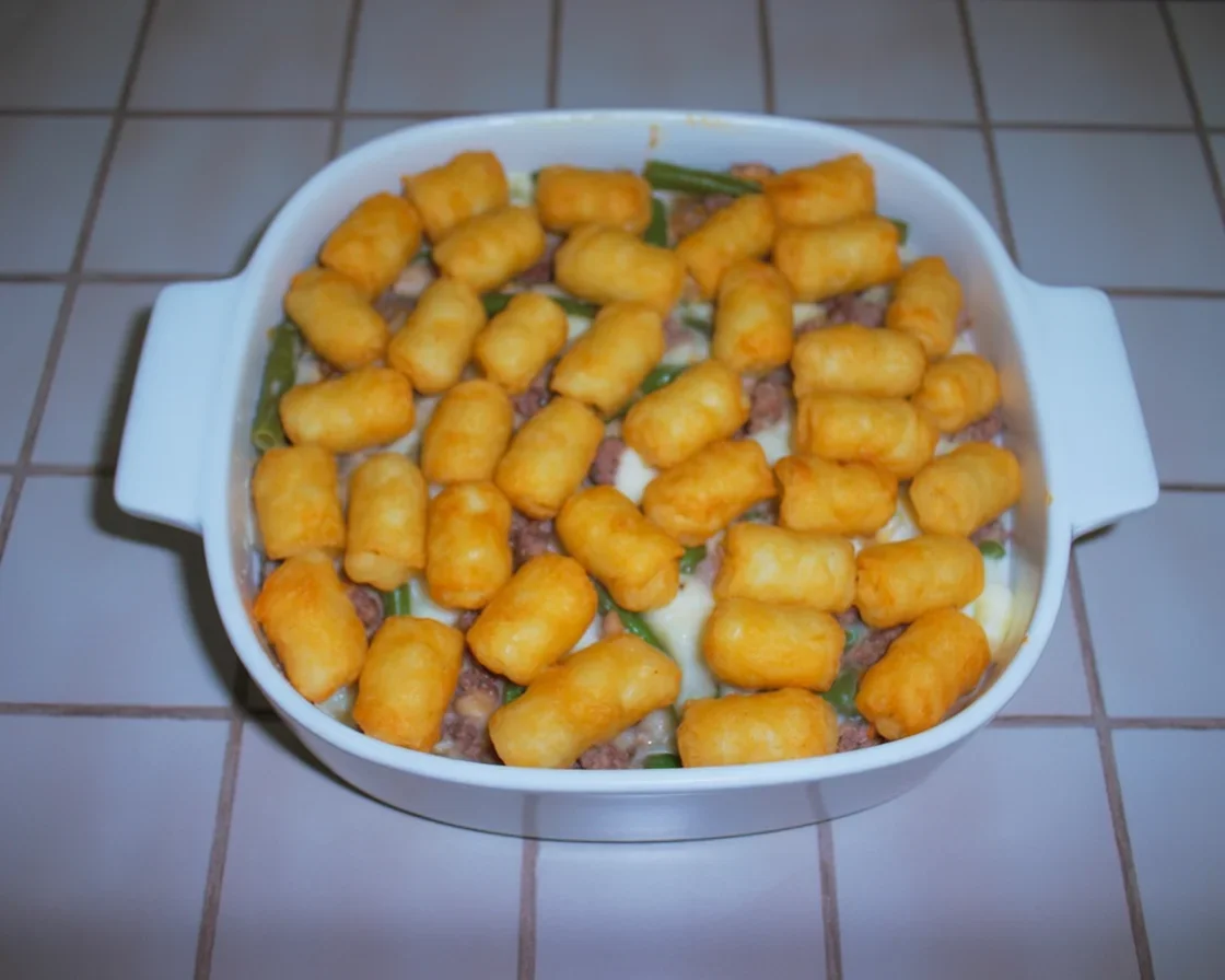 Hamburger Green Bean Casserole topped with melted cheese and green beans, served in a dish.