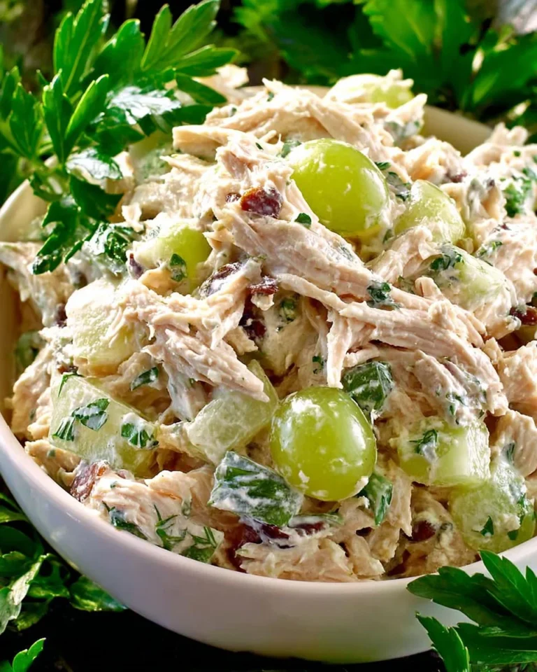 Chicken salad with grapes and walnuts in a bowl, garnished with fresh greens.