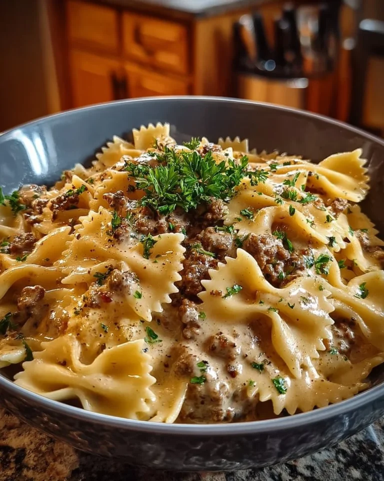 Creamy beef and bowtie pasta dish garnished with herbs