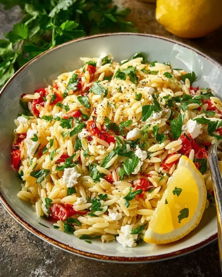 Lemon Orzo Salad with Feta, garnished with herbs on a rustic plate